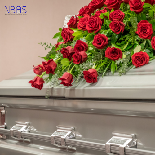 A coffin with red roses and greenery on it