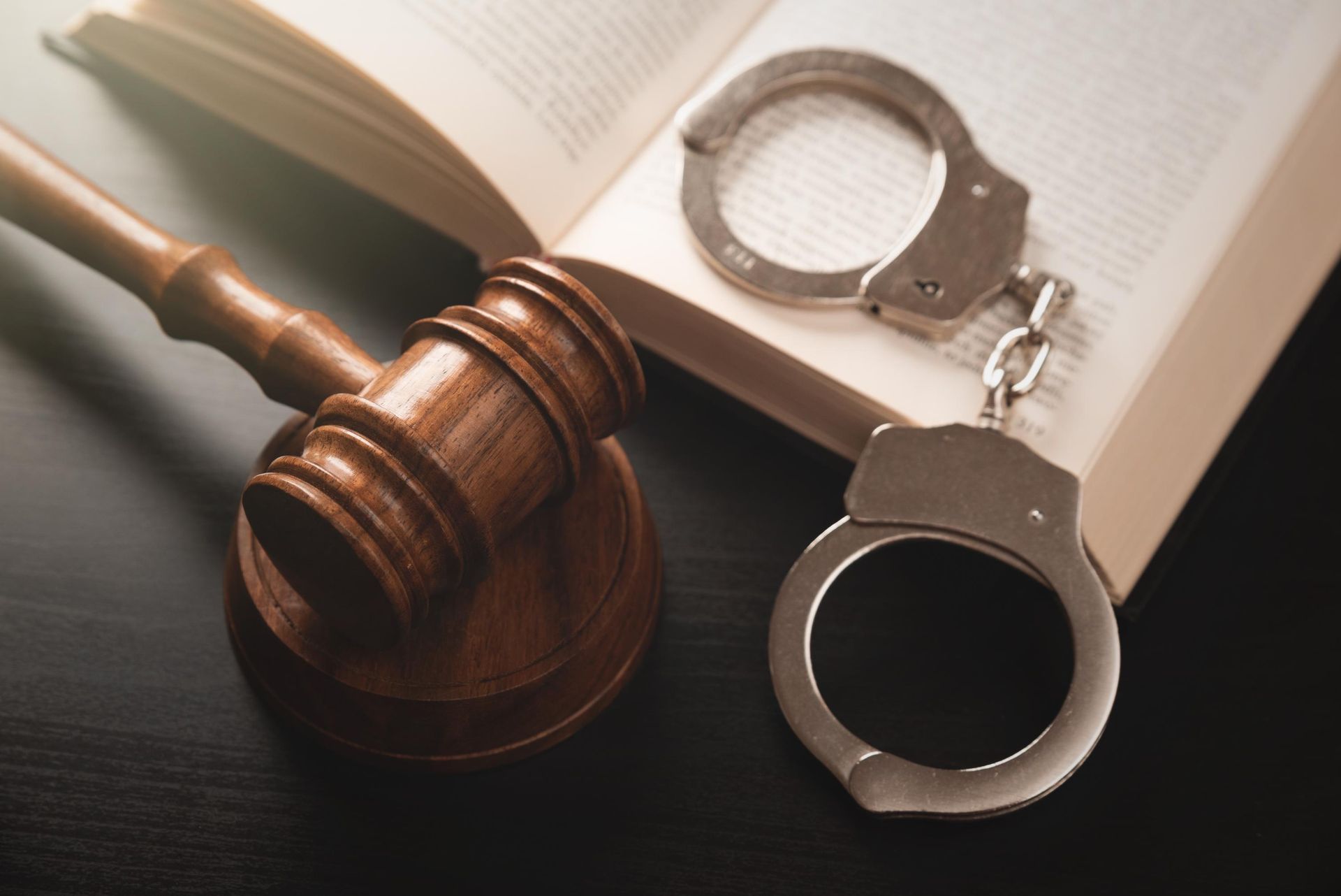 Judge’s gavel beside handcuffs on an open book, symbolizing law and justice