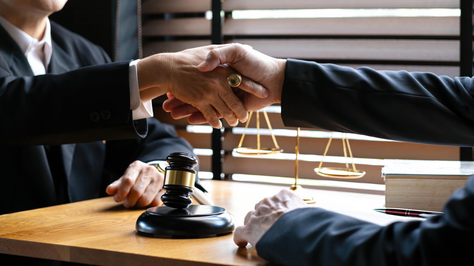 Two businesspeople shake hands over a gavel in a law office.