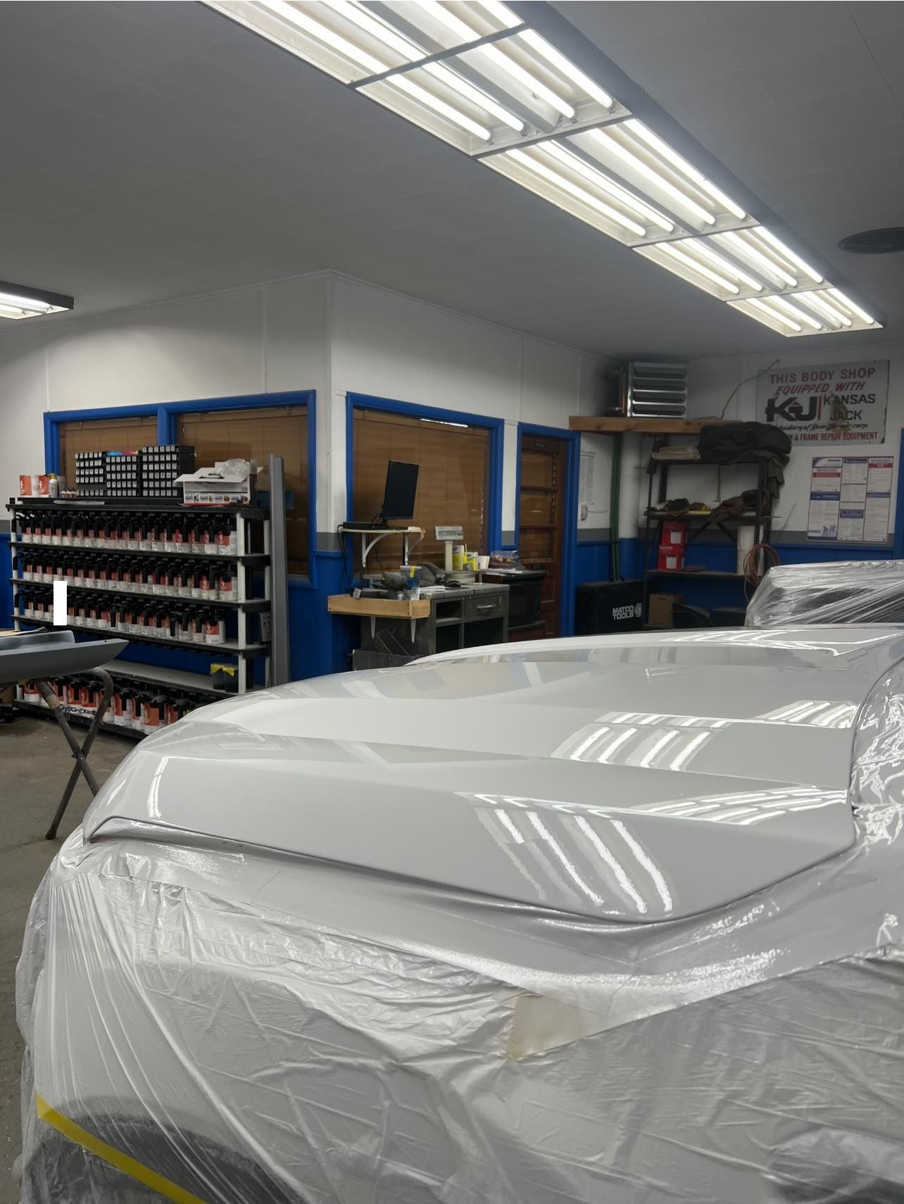 Yellow Jeep Wrangler in a garage with a tire on a ramp.