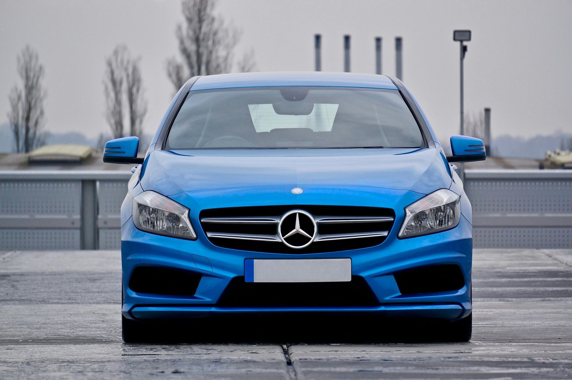 Blue Mercedes-Benz car parked on a rooftop, overcast day.