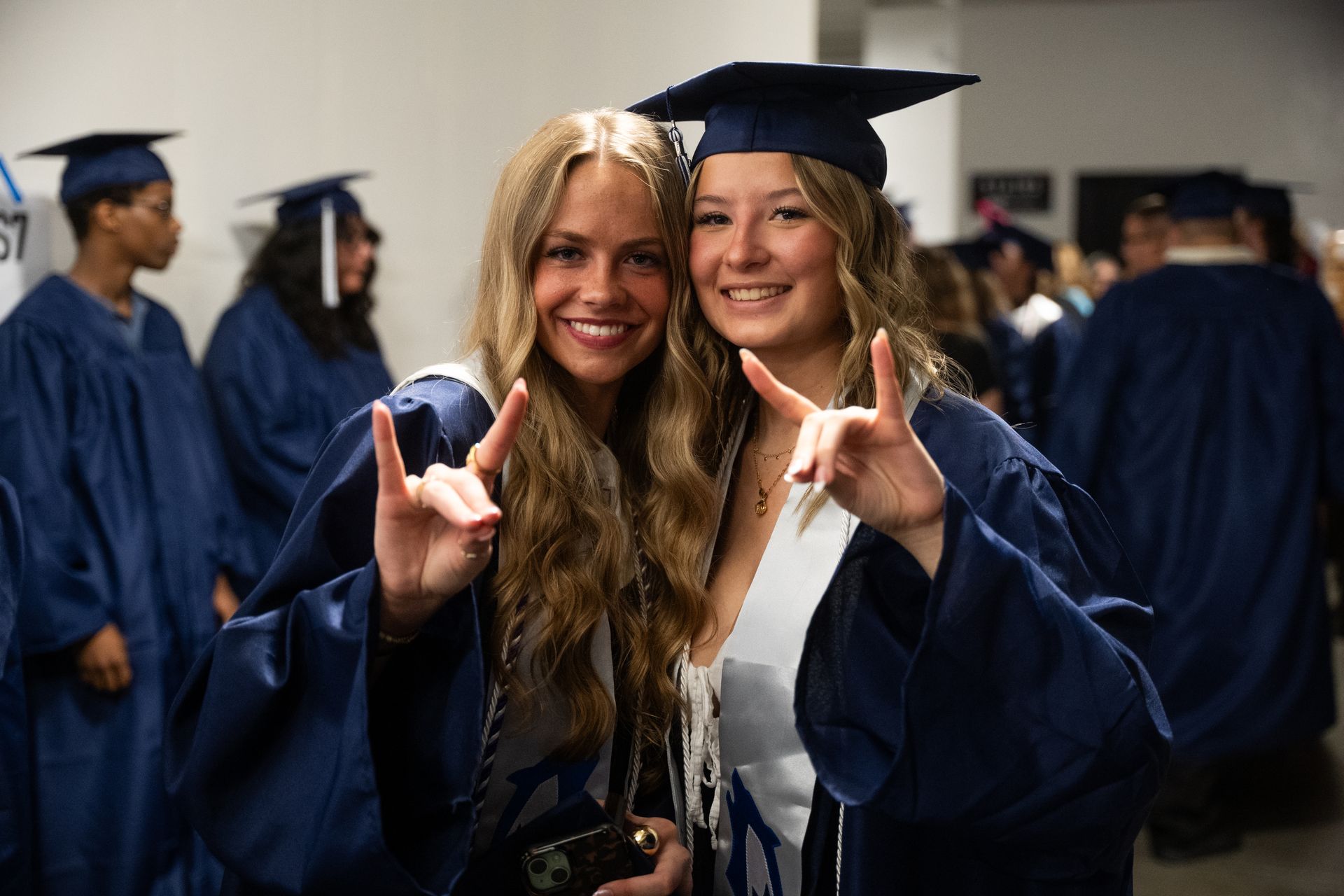 Two graduates in blue gowns and caps make the
