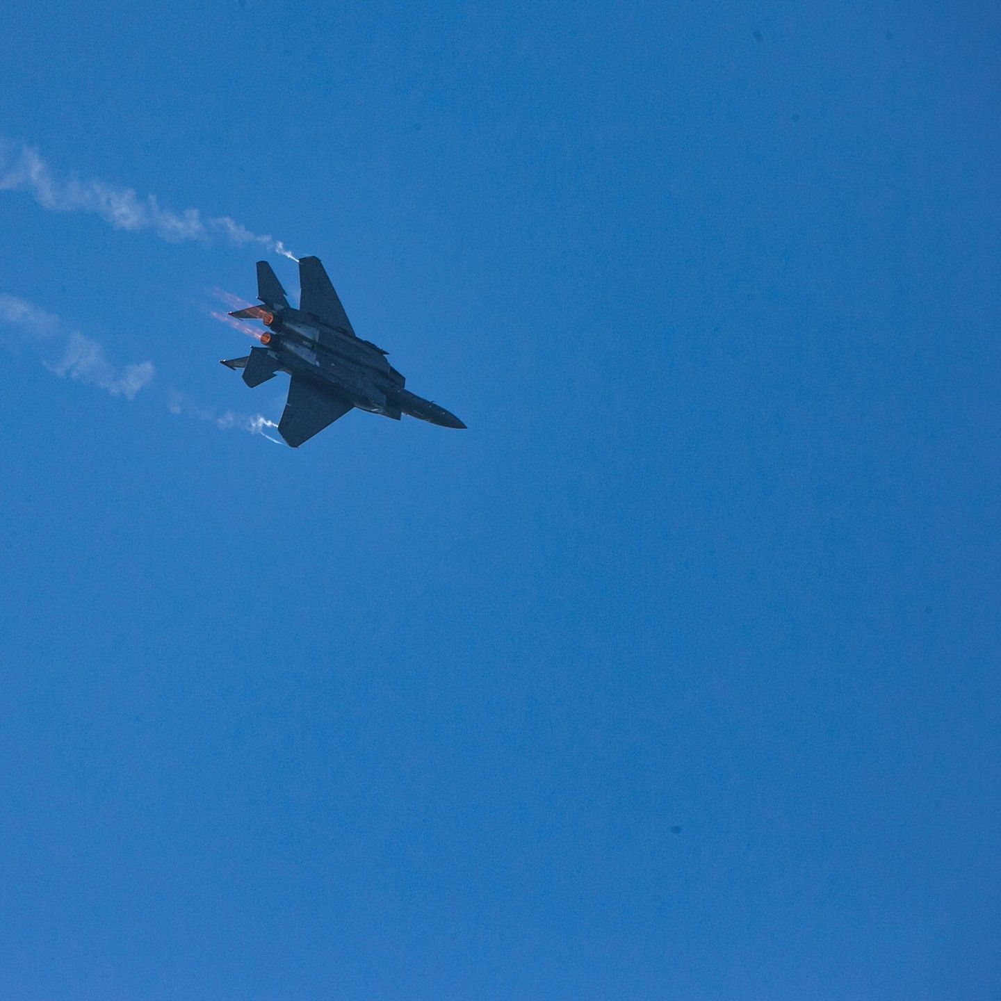 A fighter jet is flying through a clear blue sky