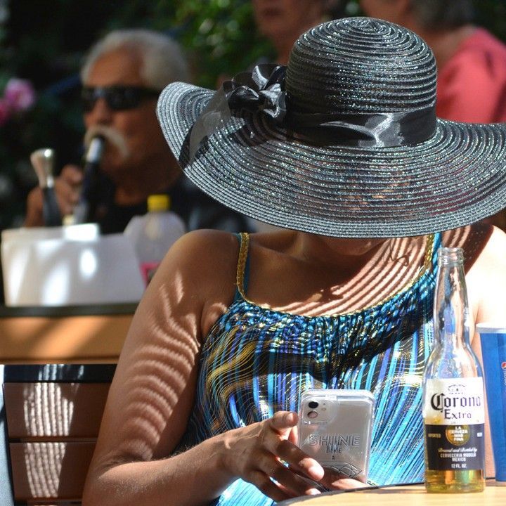 A woman wearing a hat is sitting at a table next to a bottle of corona extra