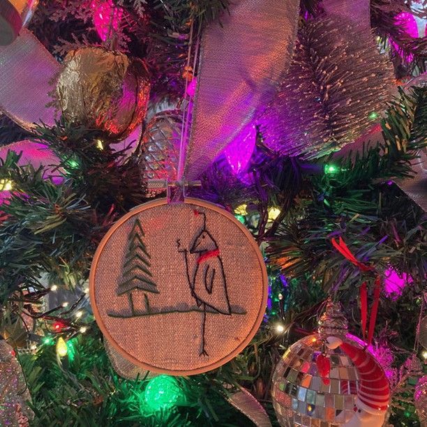 A close up of a christmas tree with a embroidered ornament on it.
