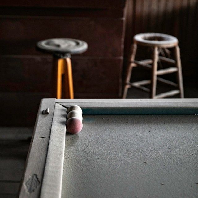 A pool table with two stools in the background