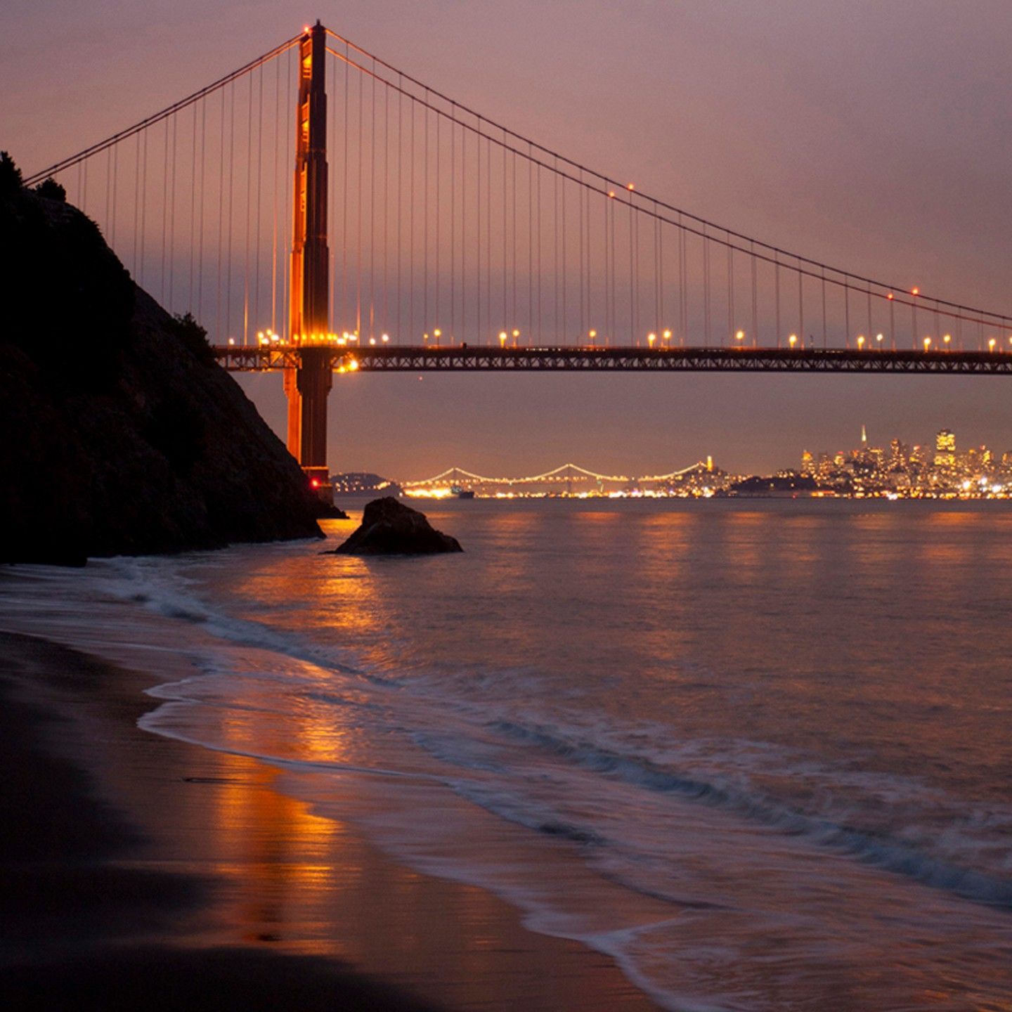 The golden gate bridge is lit up at night