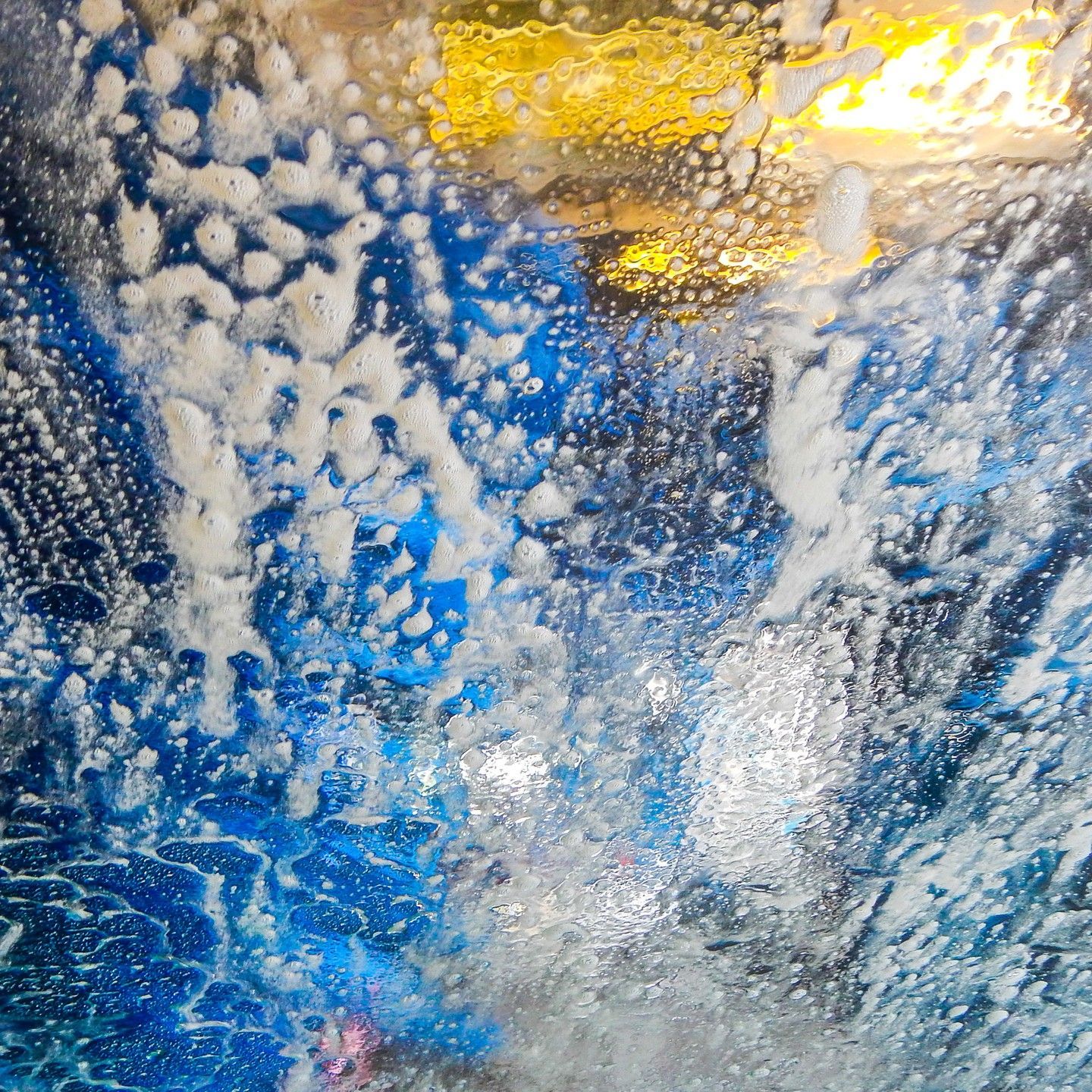 A car is being washed in a car wash with foam coming out of the window.