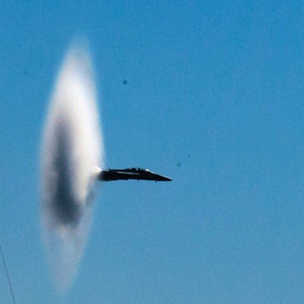 A jet is flying through a cloudy blue sky