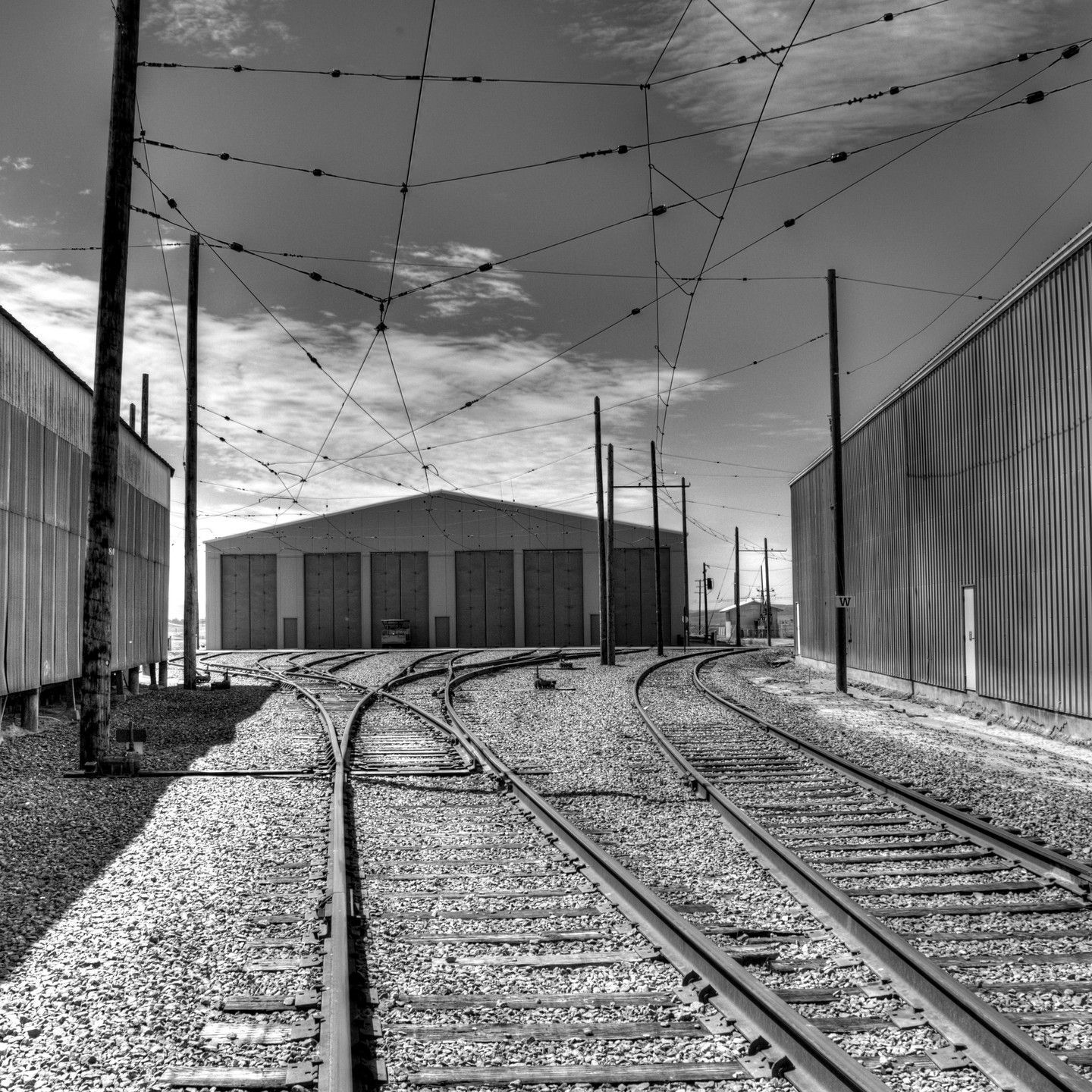 A black and white photo of train tracks with a building in the background