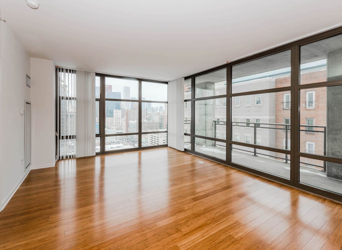 An empty living room with hardwood floors and lots of windows