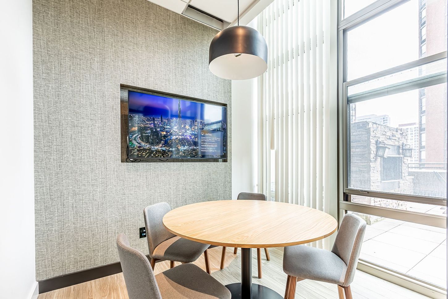 A room with a round table and chairs and a flat screen tv on the wall.