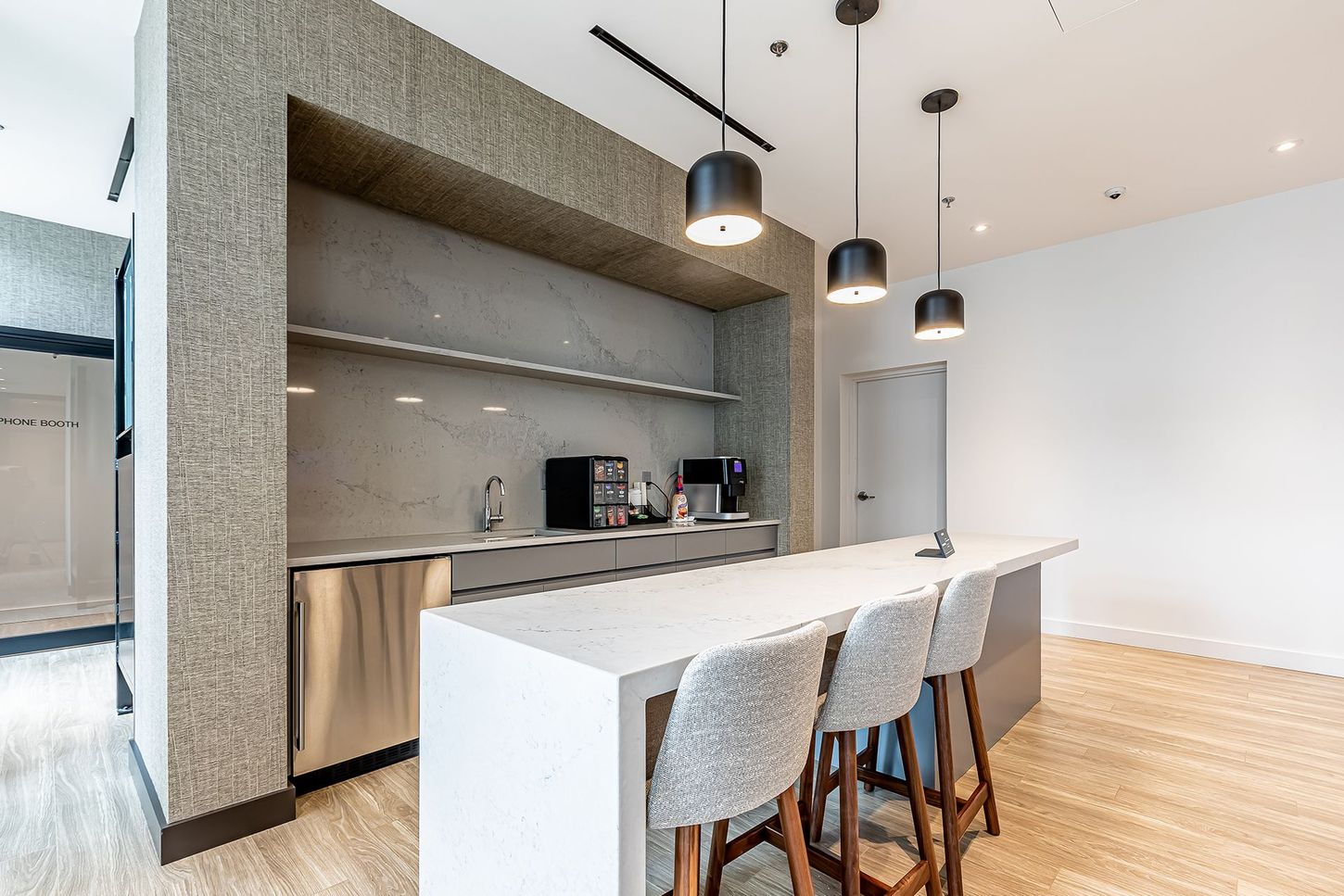 A kitchen with a large island , stools and a refrigerator.