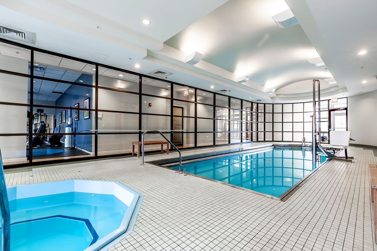 A large indoor swimming pool with a jacuzzi next to it.