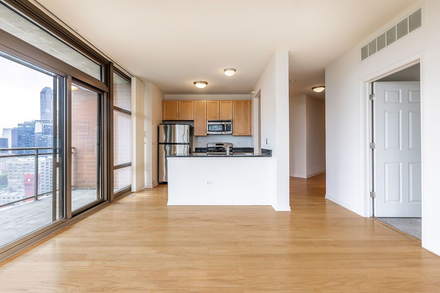 An empty apartment with a kitchen and a balcony