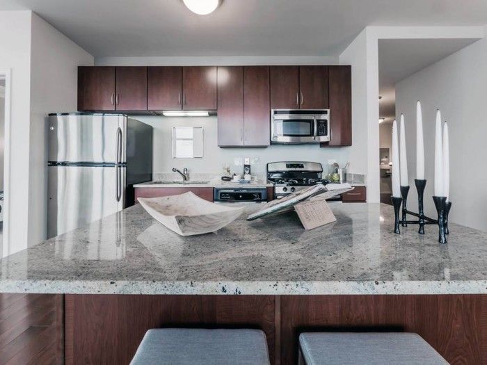 A kitchen with a stainless steel refrigerator and a granite counter top