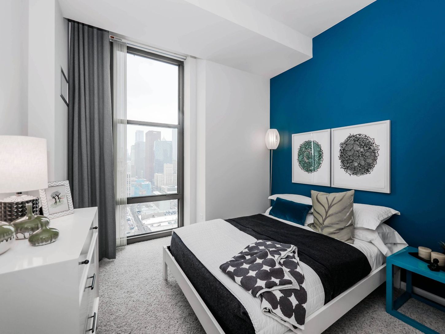 A bedroom with a bed , dresser , nightstand and blue walls.