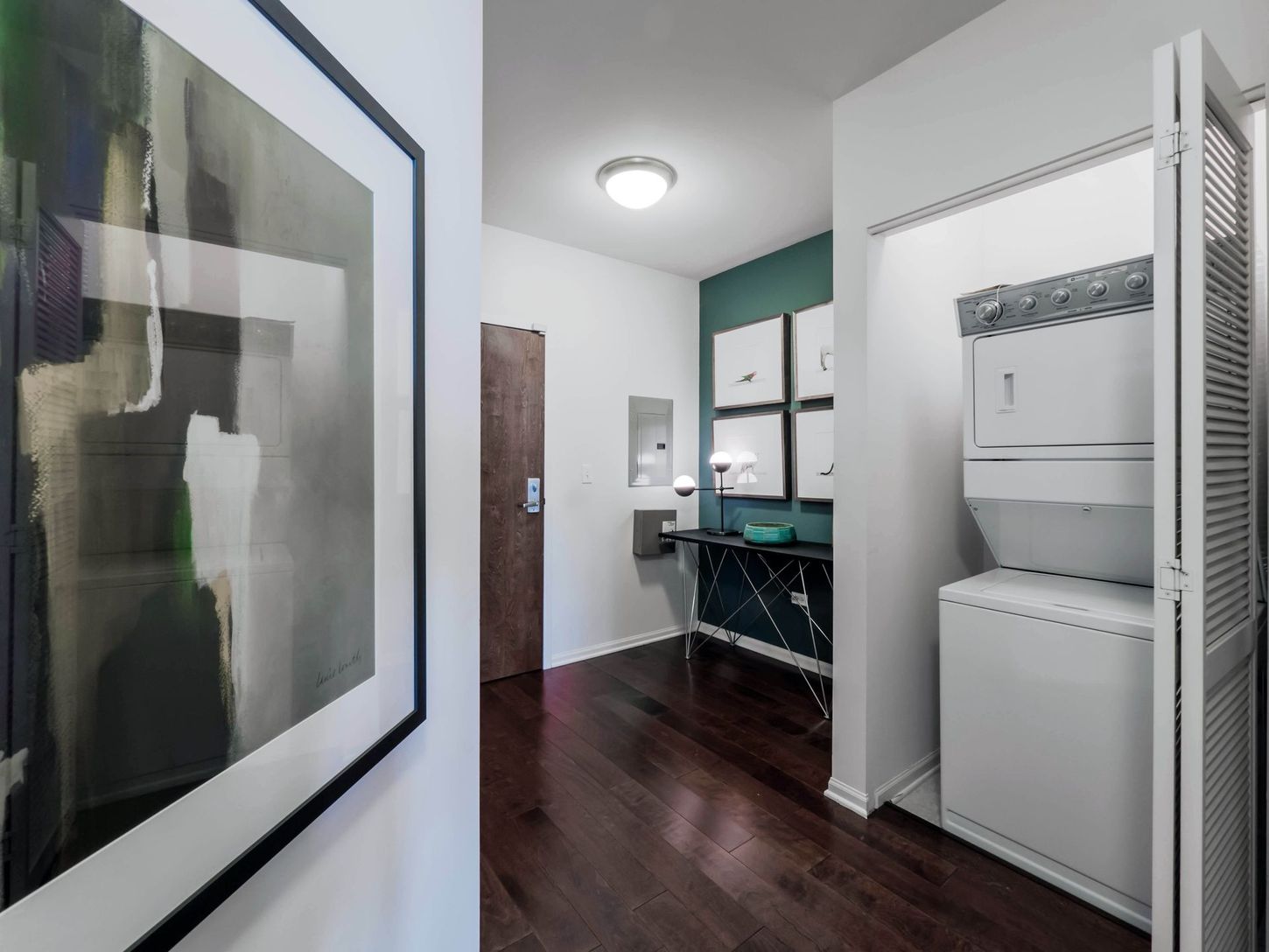 A hallway with a washer and dryer and a picture on the wall.