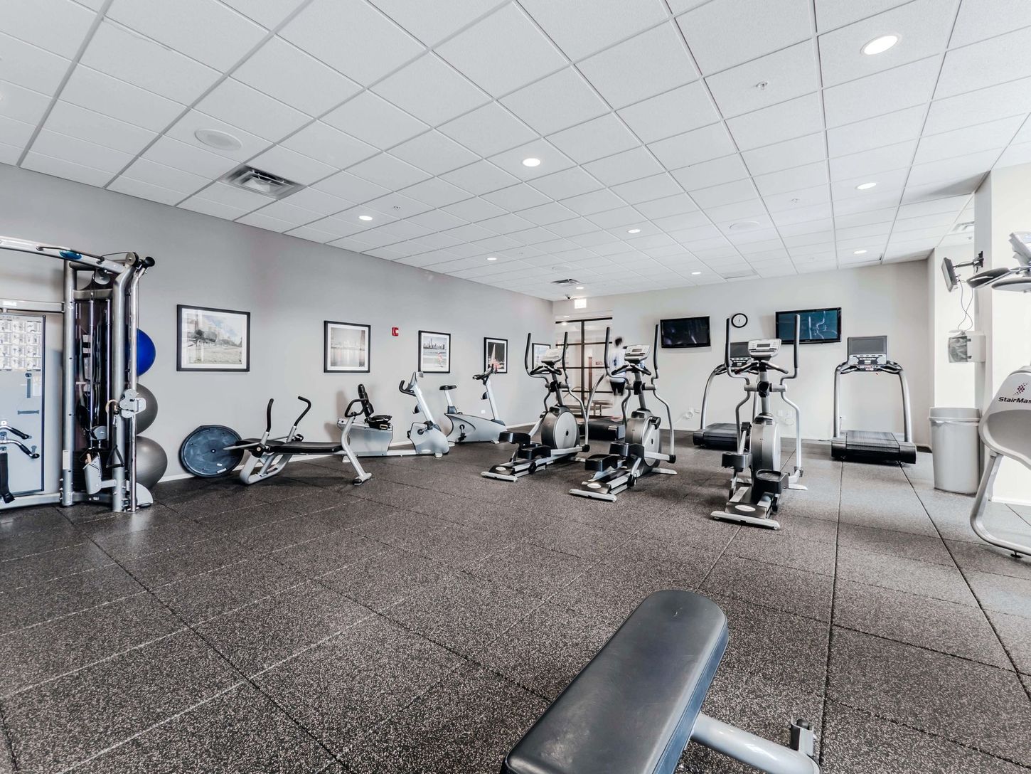 A large gym with a lot of exercise equipment and a bench.