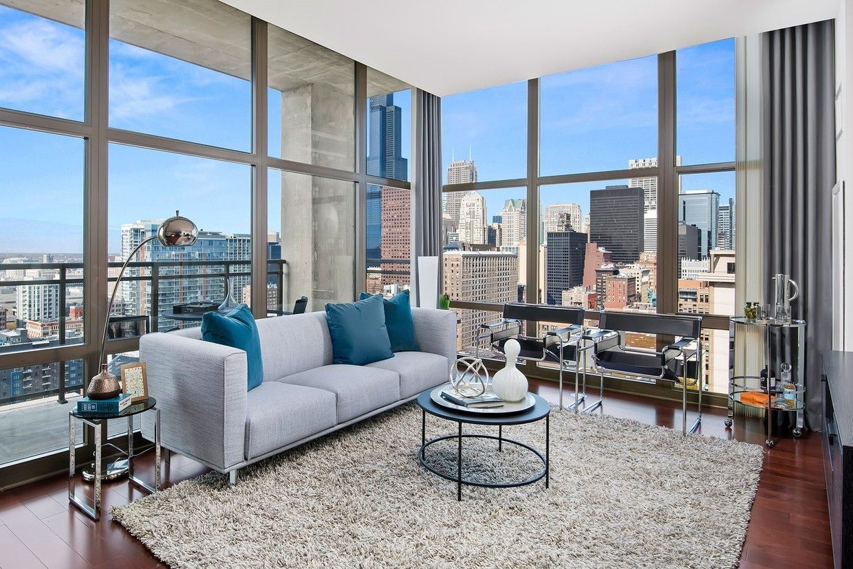 A living room with a couch , coffee table , and large windows.