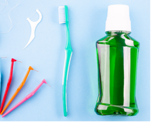 Dental hygiene tools: toothbrush, floss, interdental brushes, and mouthwash on a blue surface.