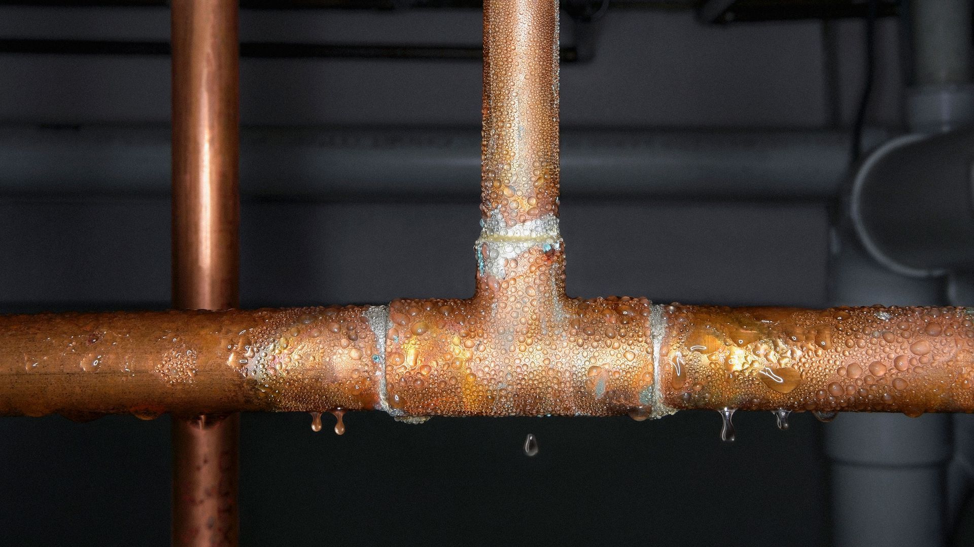 Frozen copper pipes with icicles, in a wooden, indoor setting.