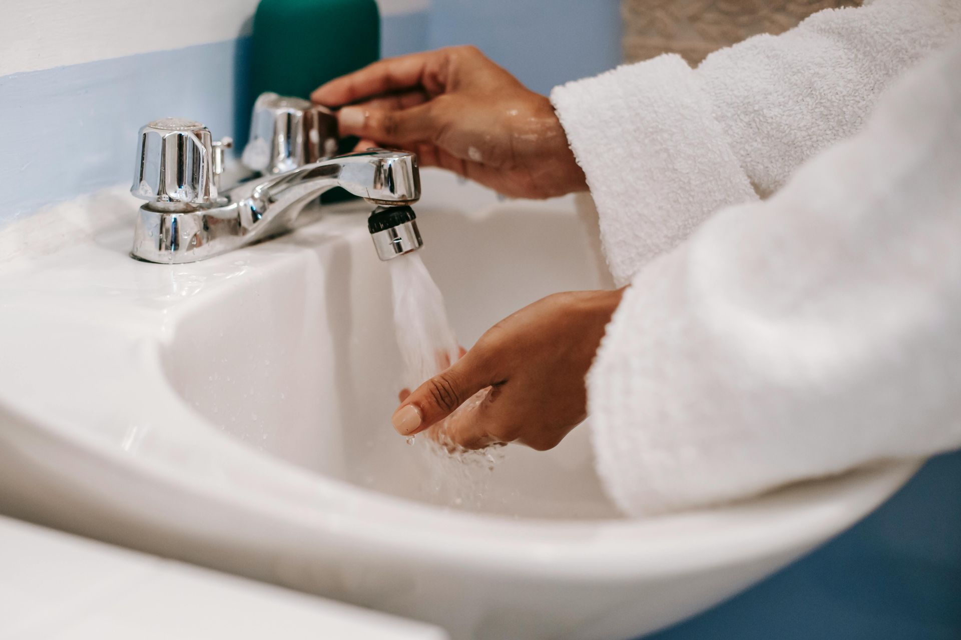 A person is washing their hands in a bathroom sink.
