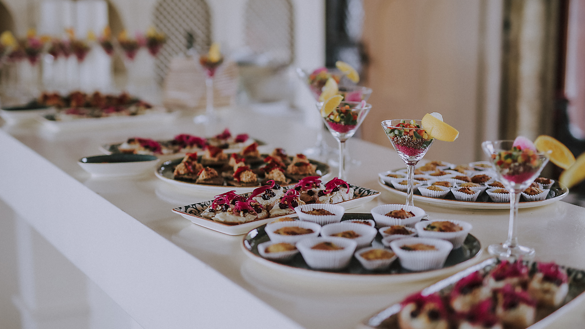 Dessert buffet with assorted pastries and fruit-topped cups on a white table at an elegant event