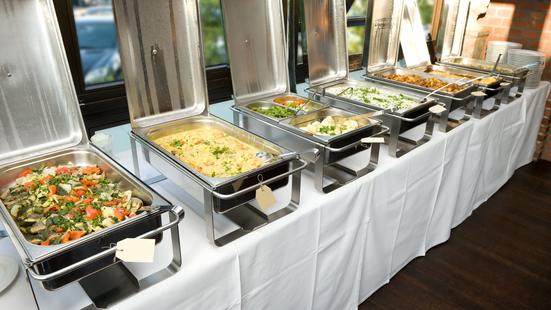 Buffet table with stainless steel trays of assorted hot dishes at a catered event