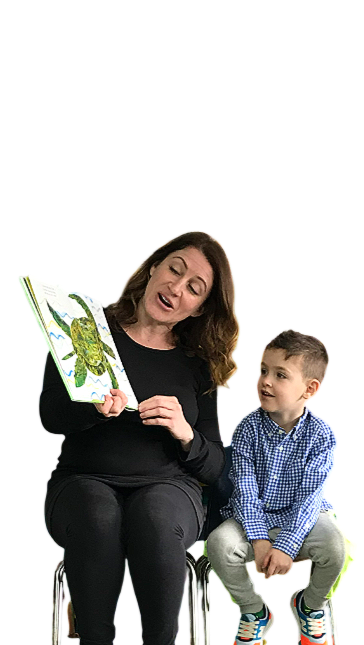 Boy with curly brown hair smiling, wearing a white shirt.