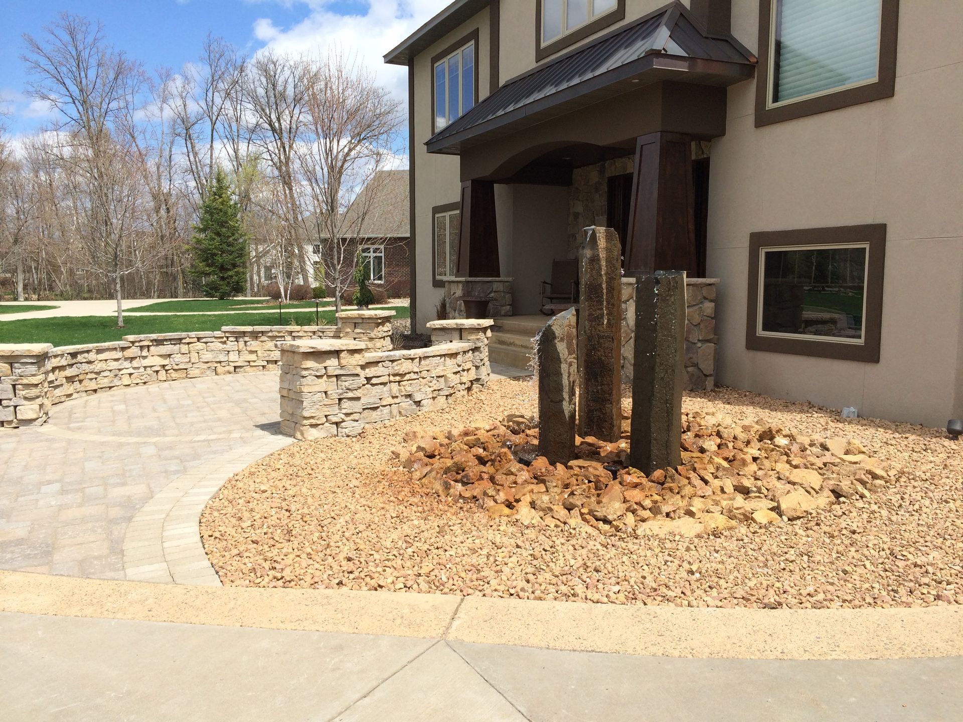 Landscaped front yard with stone walkway, rock beds, and a house porch