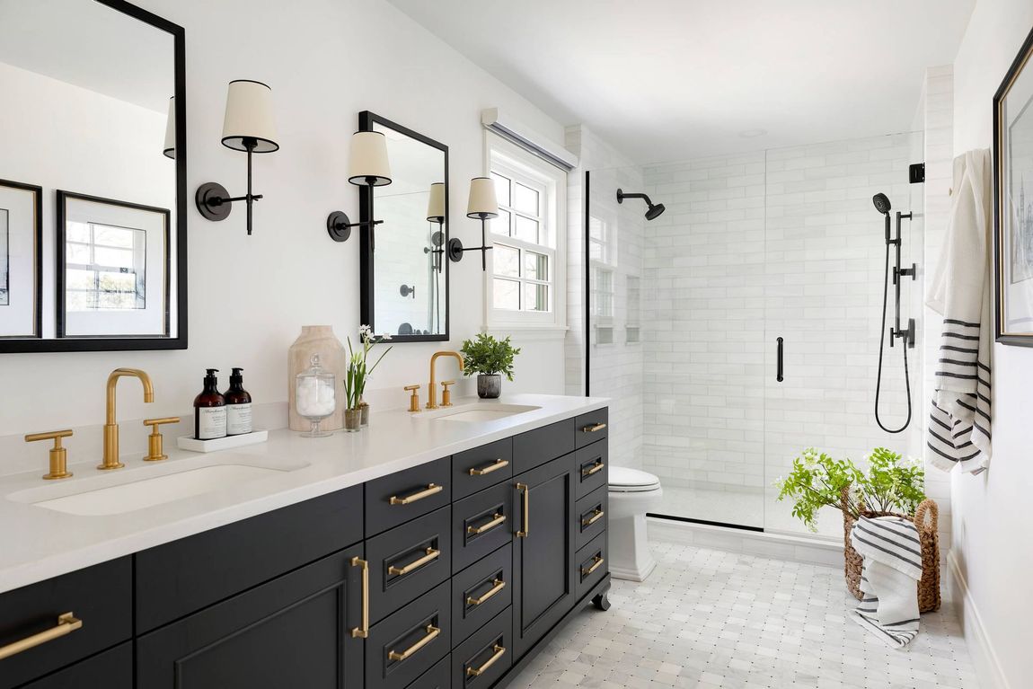 A bathroom with two sinks , a toilet , and a walk in shower.