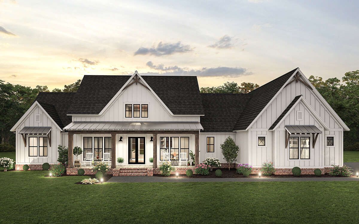 A large white house with a black roof is sitting on top of a lush green field.