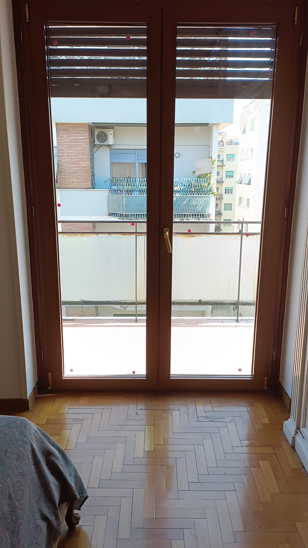 Le doppie porte in legno si aprono su un balcone. La luce del sole filtra attraverso i vetri.