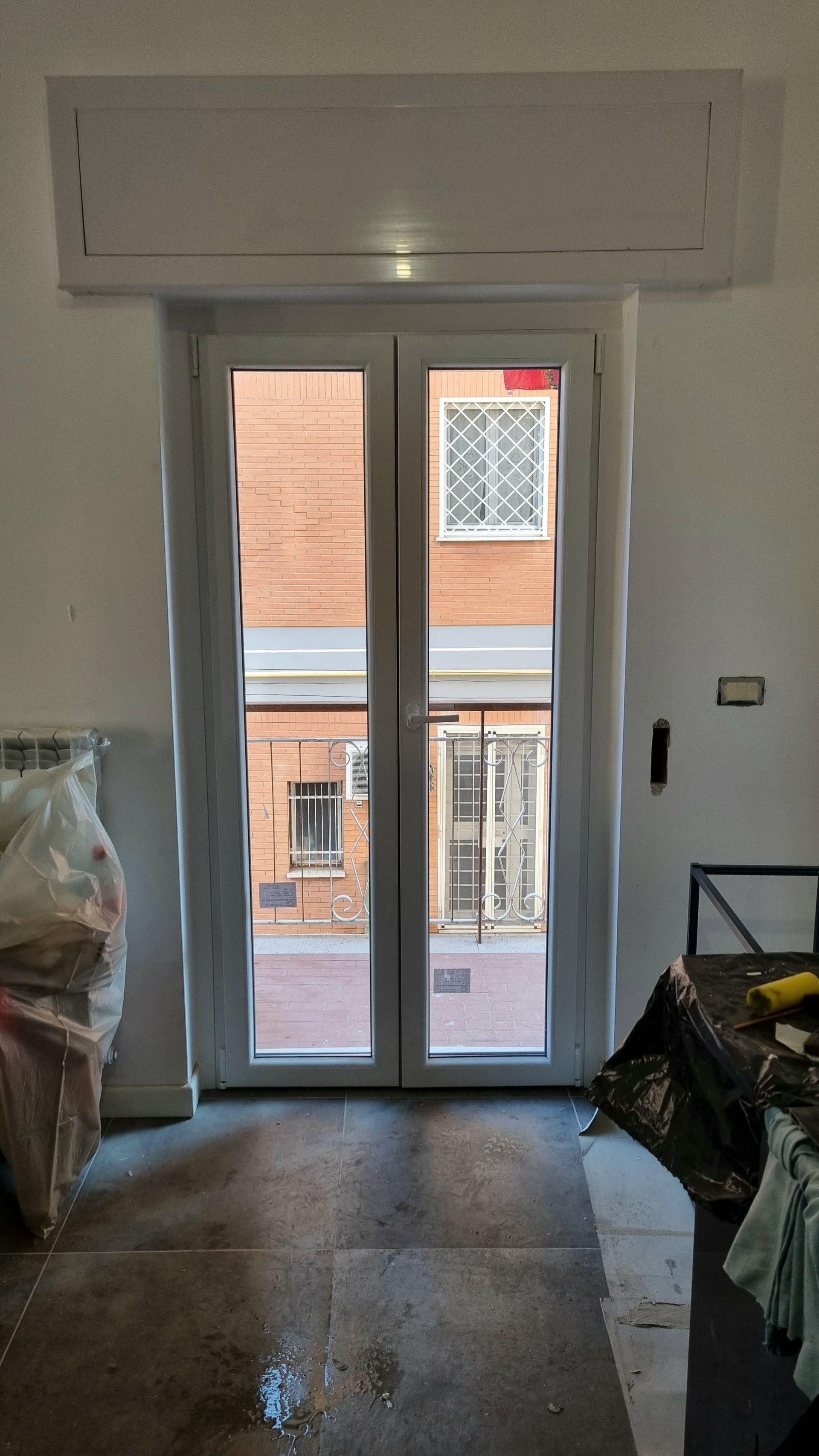 Vista interna di una porta a due ante che conduce a un vicolo esterno. Vista dell'edificio attraverso le finestre.