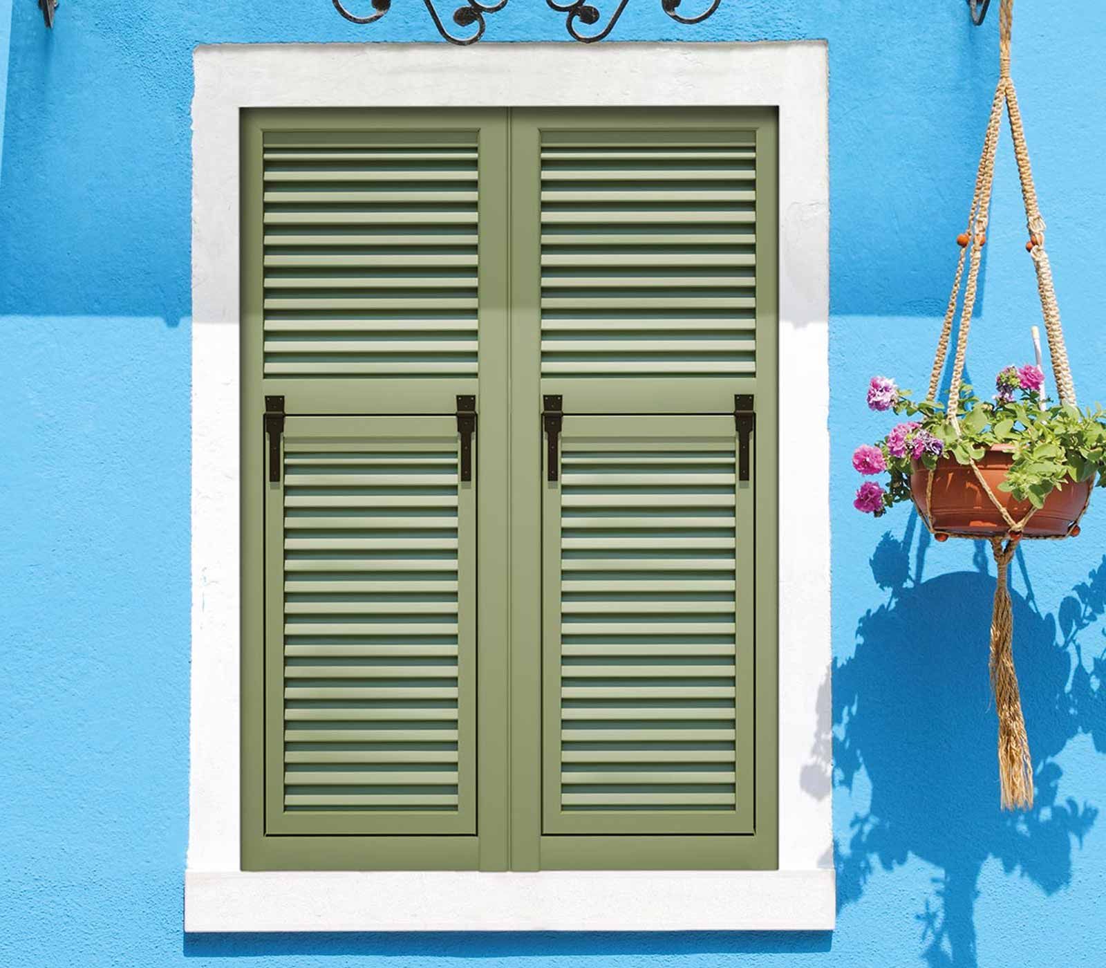 Persiane verdi su un edificio blu, vaso di fiori appeso.