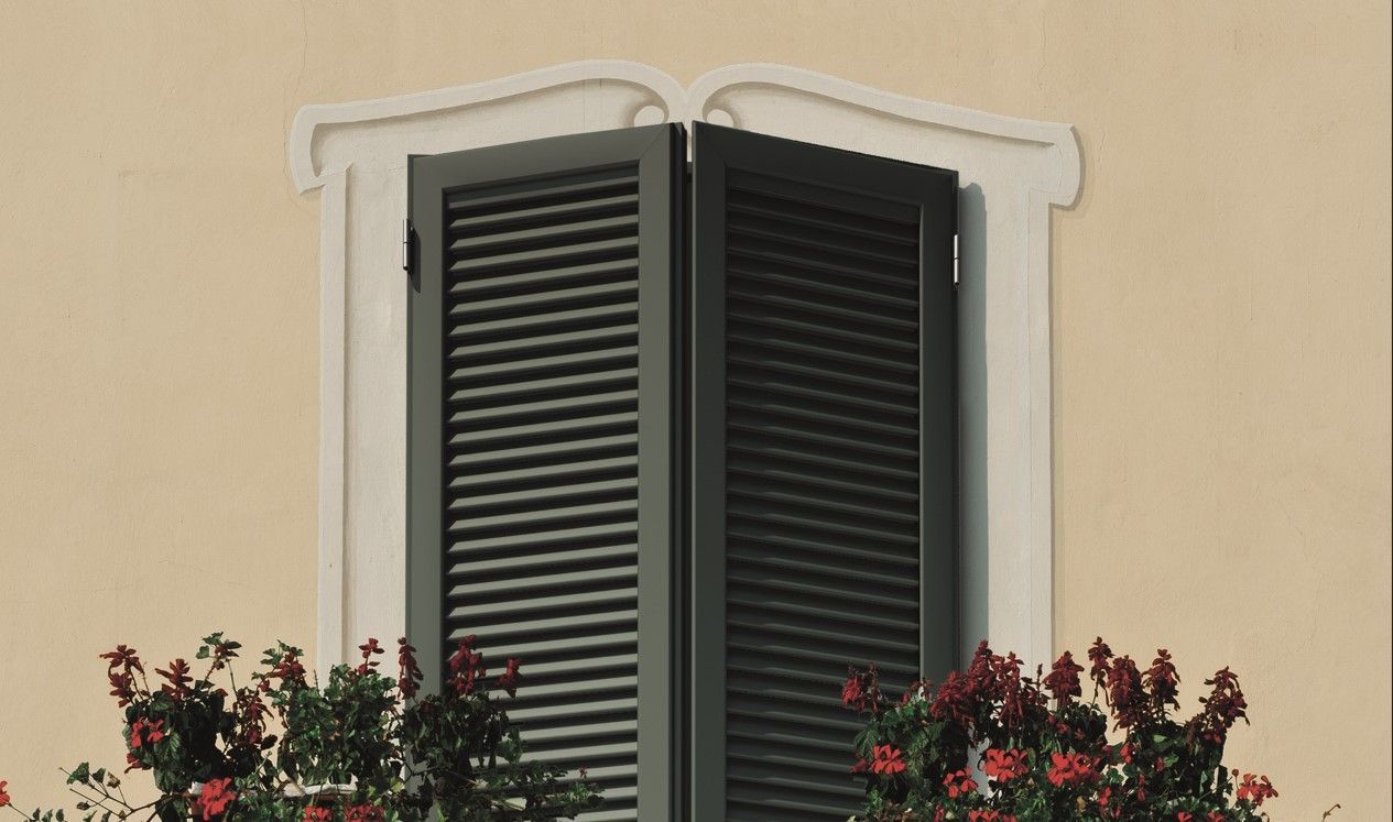 Finestra con persiane scure e fiori rossi davanti. Prodotti PERSIANE 2RB SOLUTION Roma