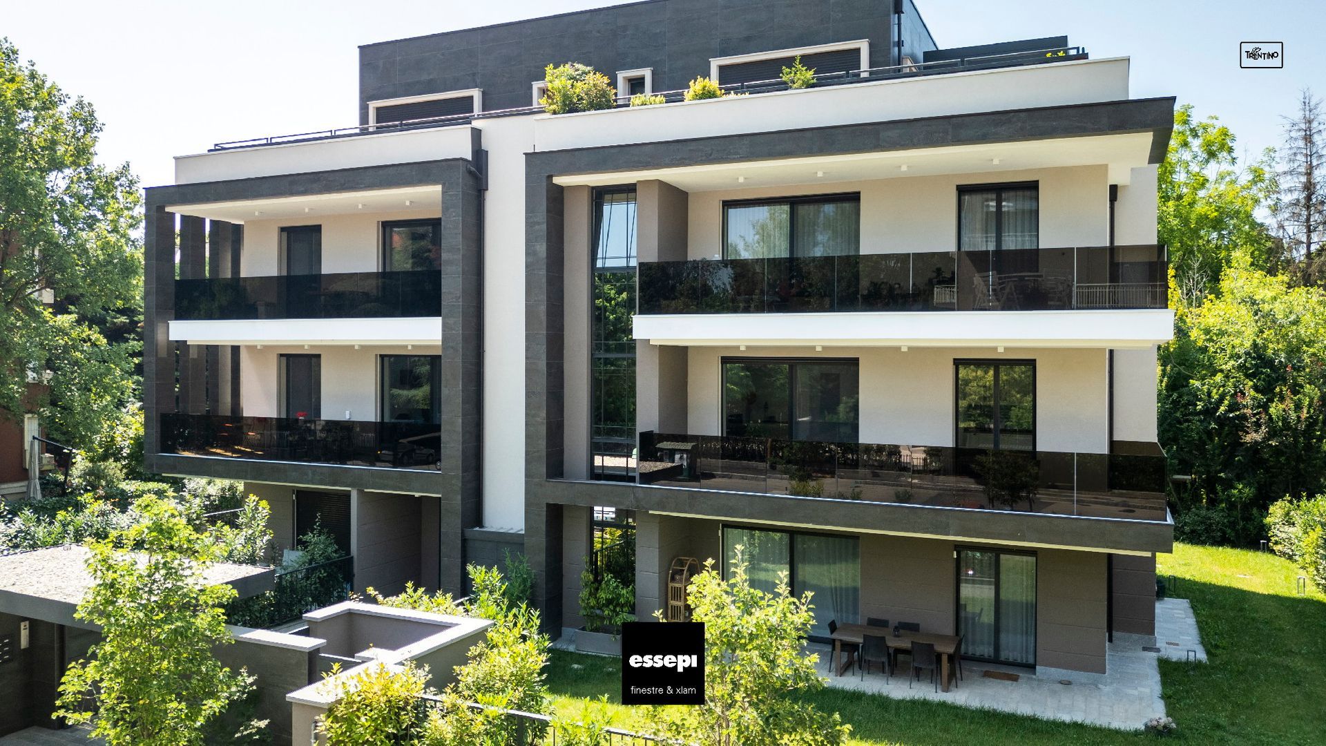 Moderno condominio con balconi, immerso nel verde.