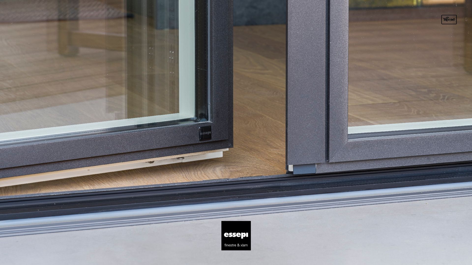 Primo piano di una porta scorrevole in vetro con cornice nera e soglia bassa.