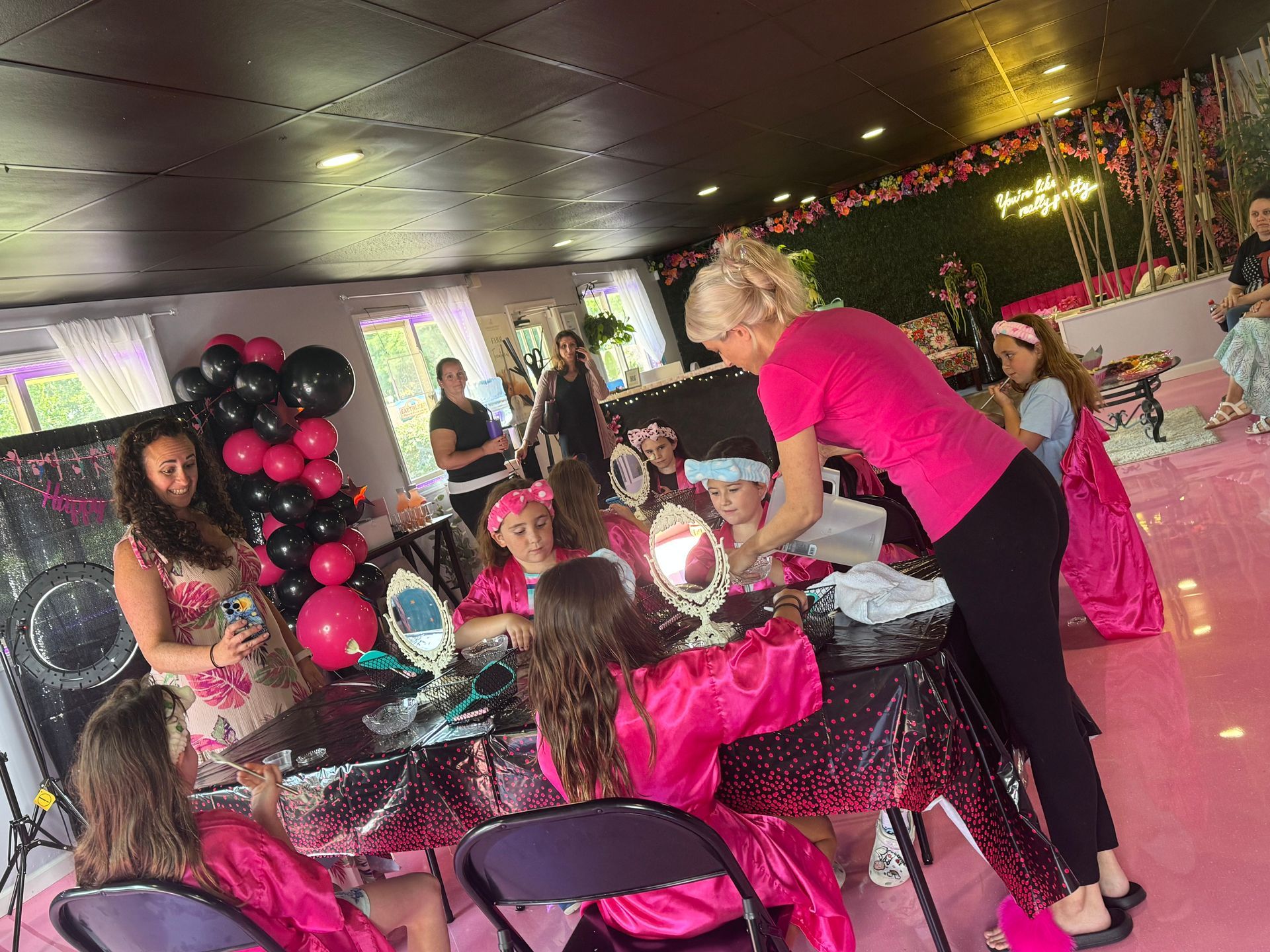 A group of girls are sitting at a table getting their hair done.