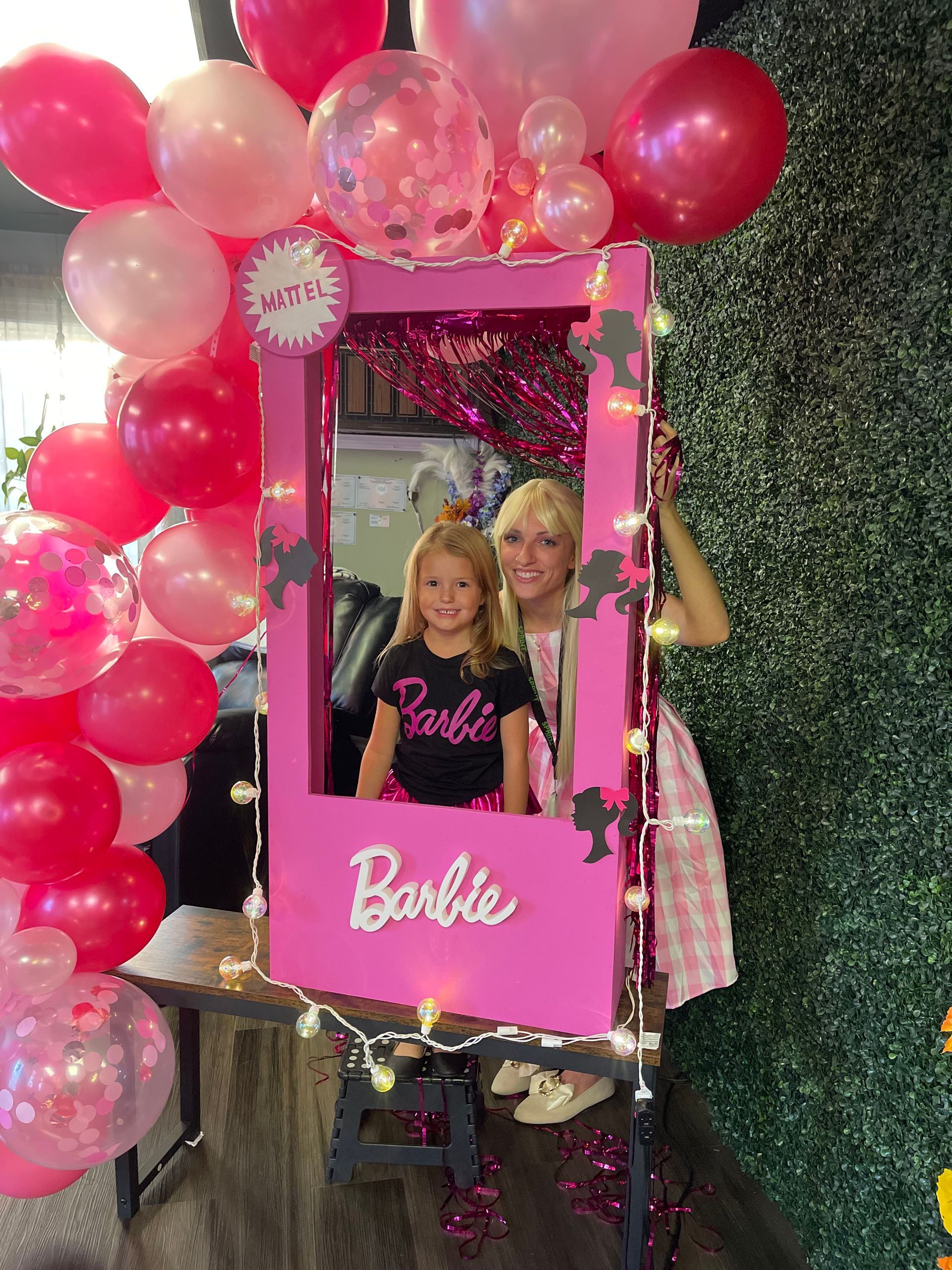 A woman and a little girl are posing for a picture in a barbie photo frame.