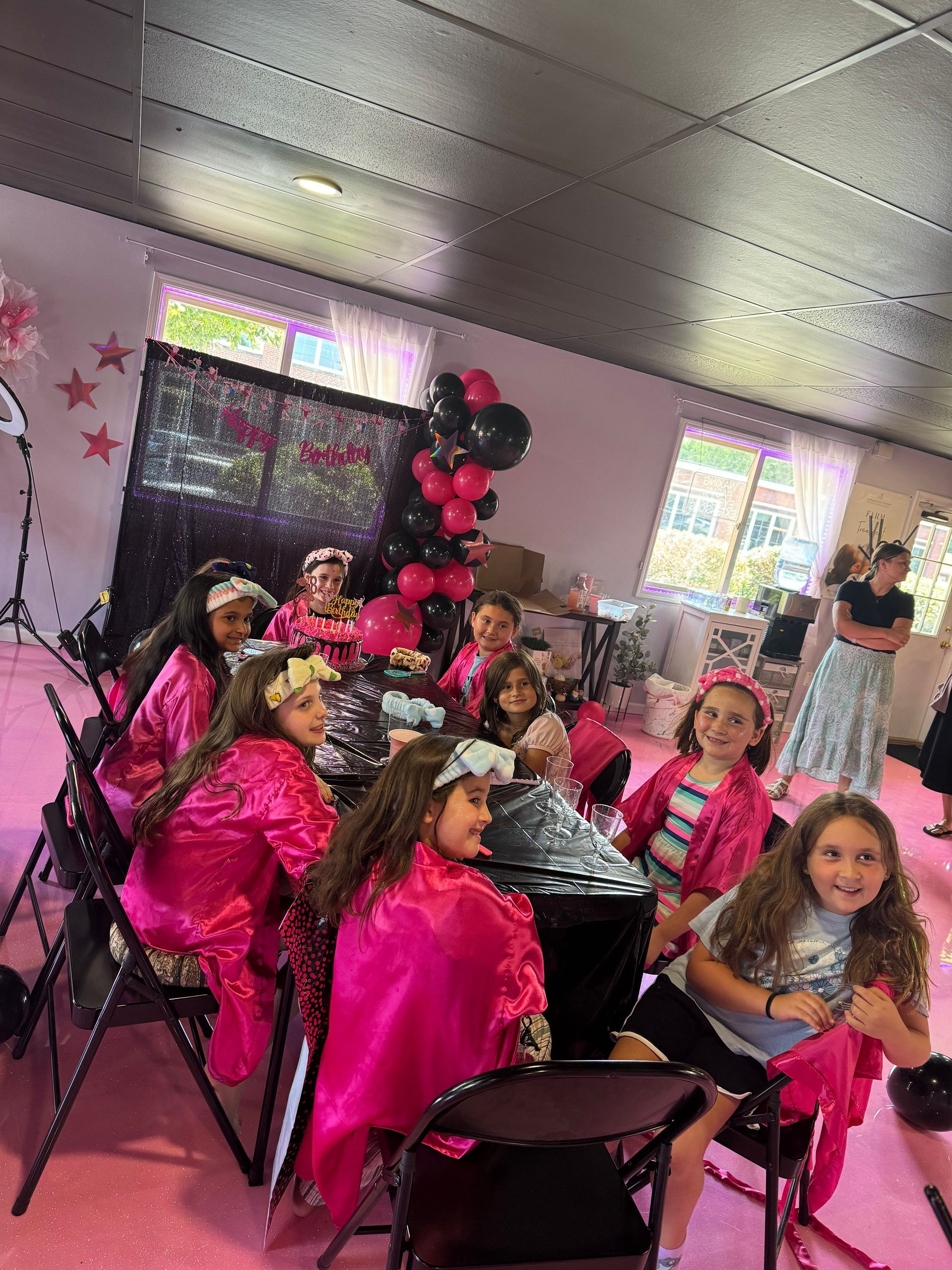 A group of young girls are sitting at a table in a room.