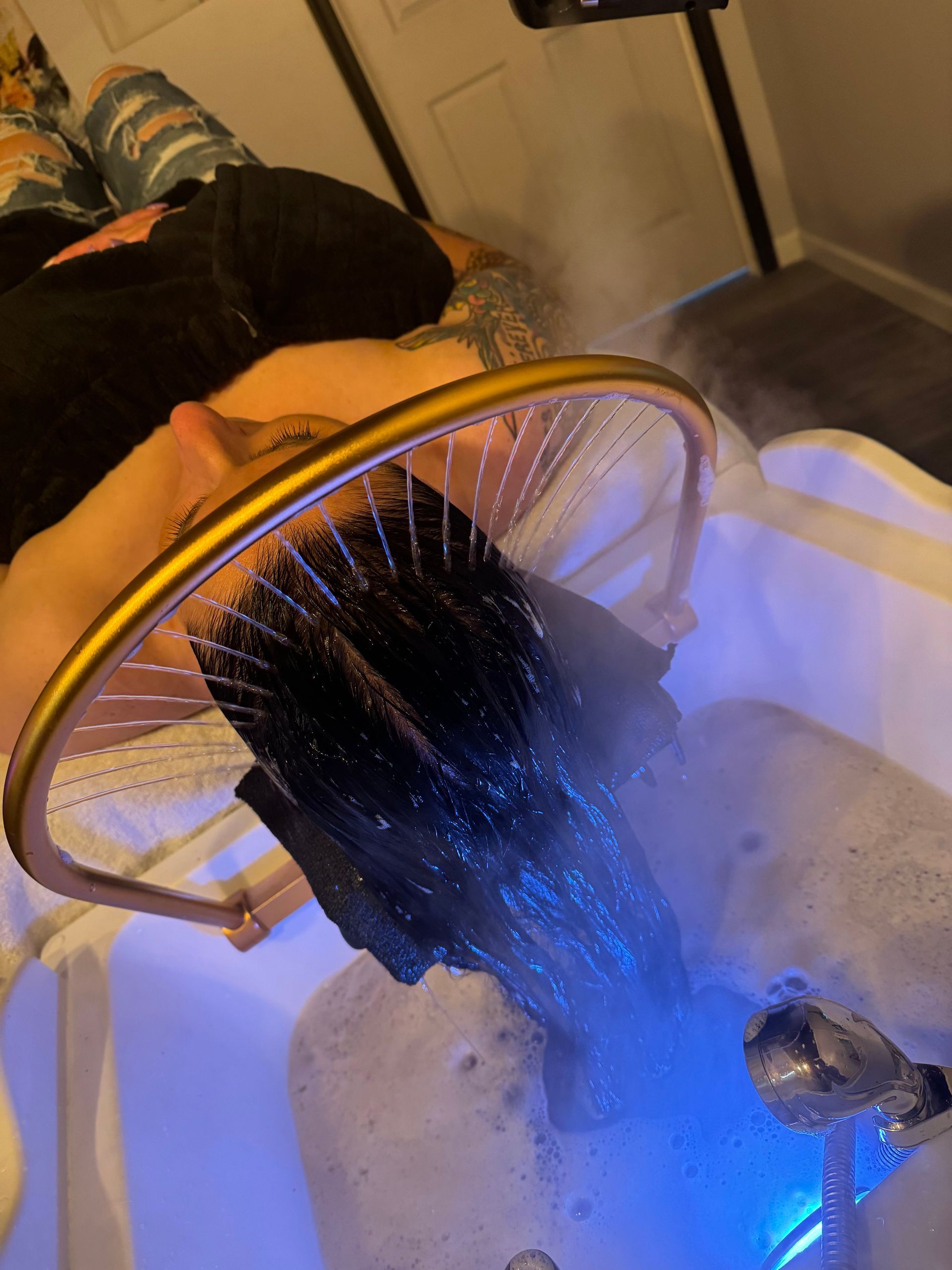 A woman is getting her hair washed in a sink.