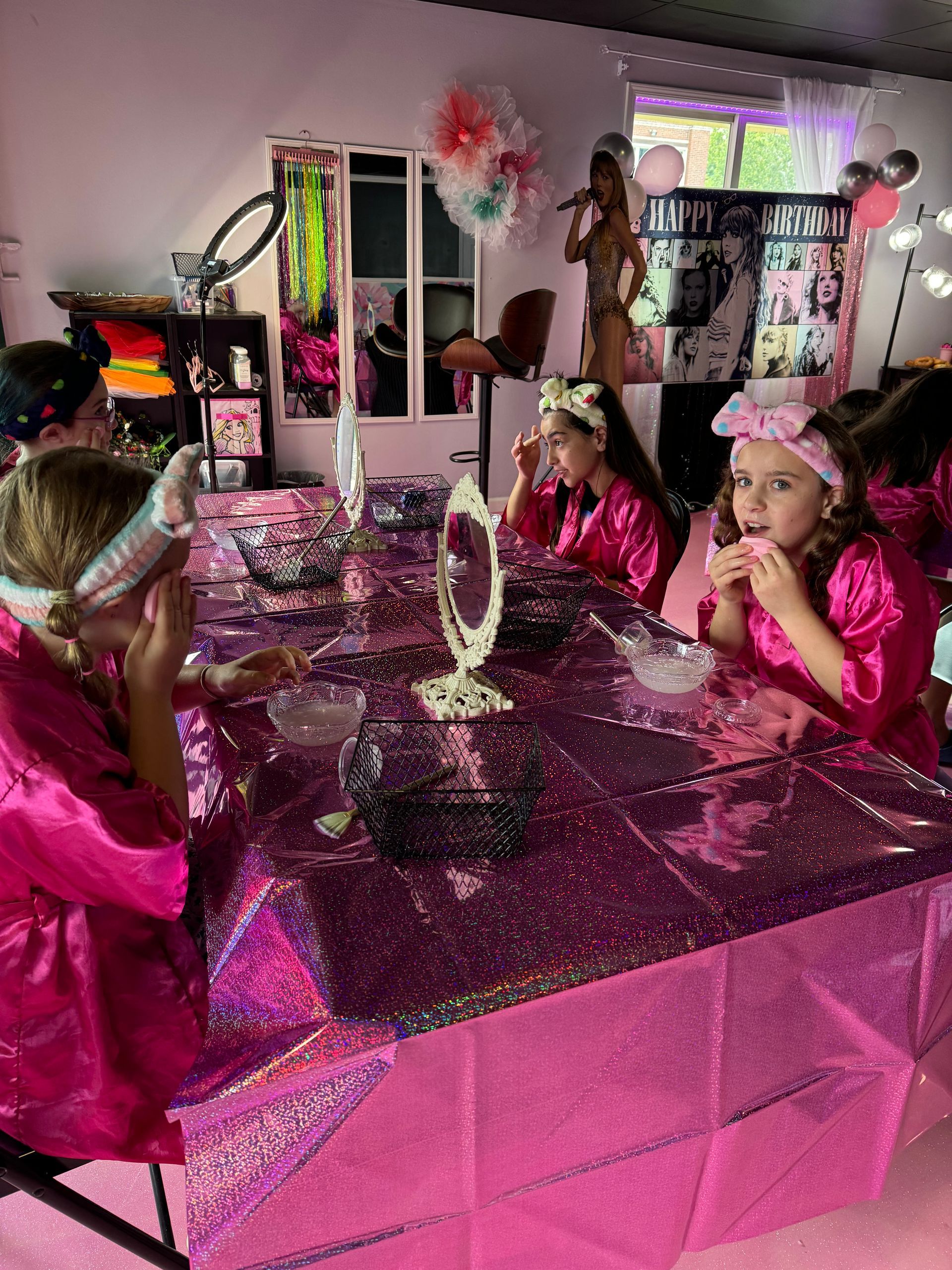 A group of young girls are sitting at a table applying makeup.