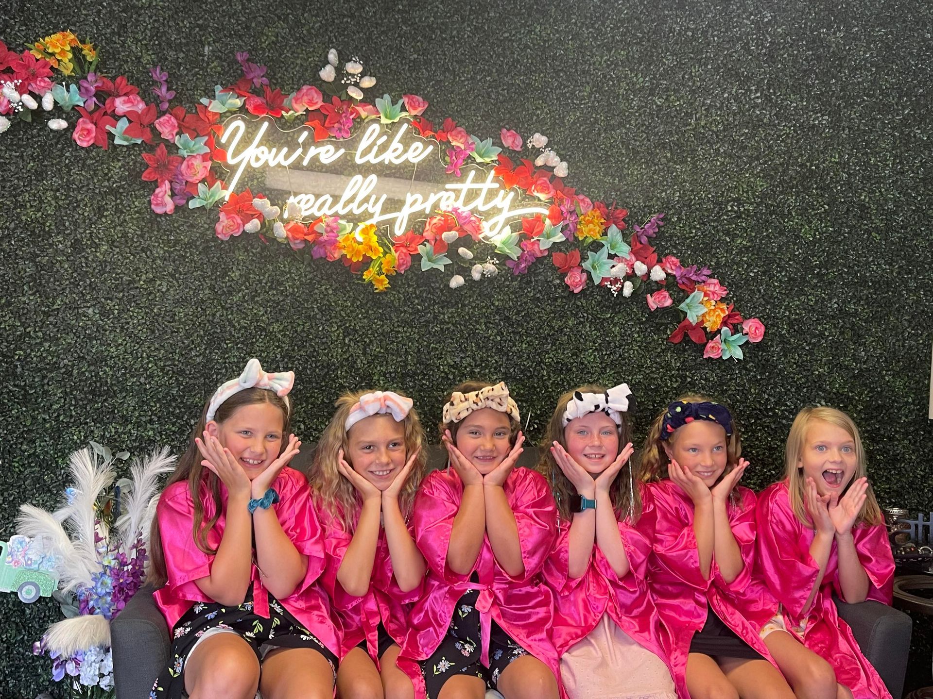 A group of young girls in pink robes are posing for a picture.