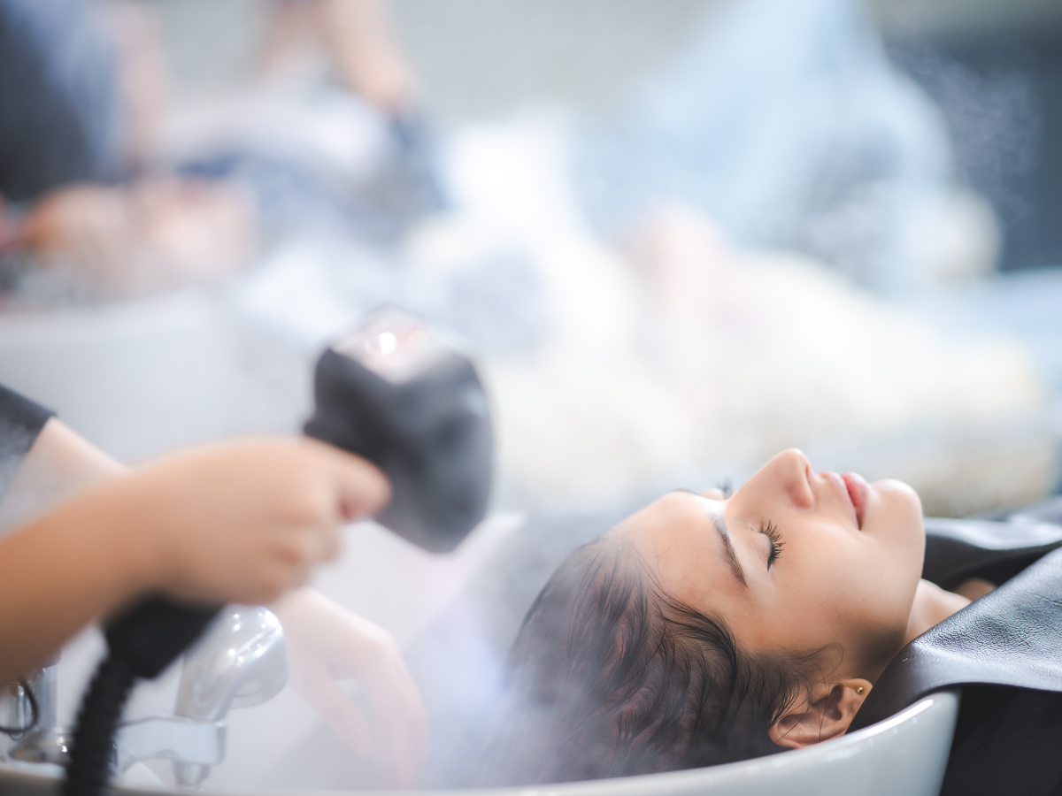 A woman is getting her hair washed in a sink at a salon.