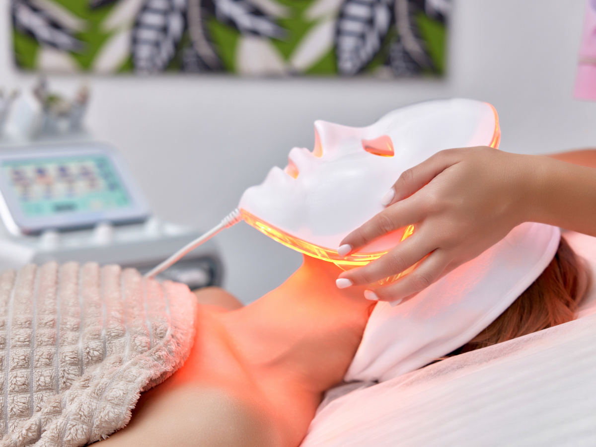 A woman is getting a light treatment on her face
