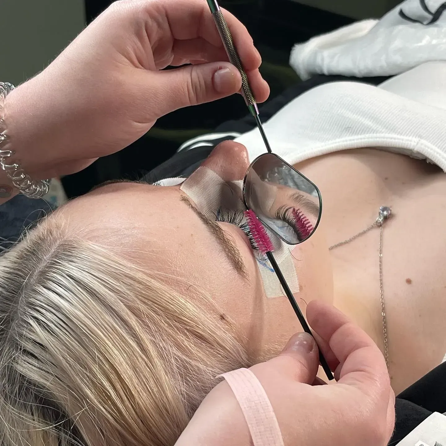 A woman is getting her eyelashes done by a lash artist