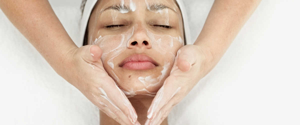 A woman with a towel wrapped around her head is getting a facial massage.