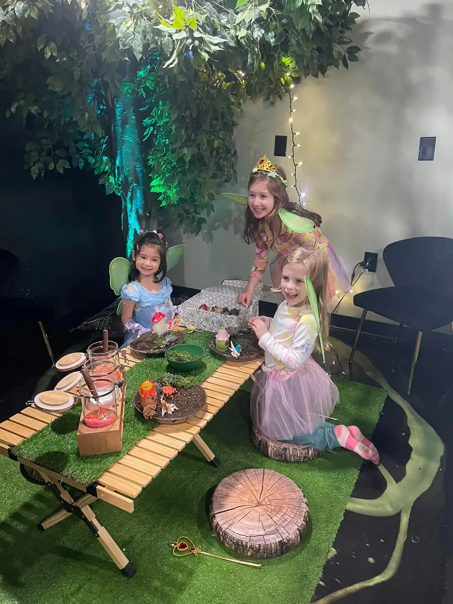 Two little girls are sitting at a table with a cake.